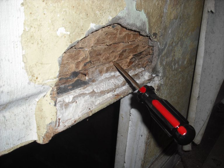 Termite damage found during a Checkmark Plus termite inspection: crumbling wood at a post